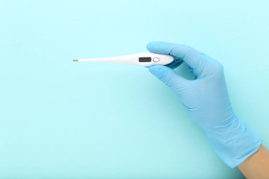 Doktor termometreyi mavi arkaplanda tutuyor