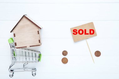 Alışveriş arabalı ev modeli ve ahşap masada satılan kelime.