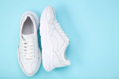 Mavi arkaplanda bir çift beyaz ayakkabı