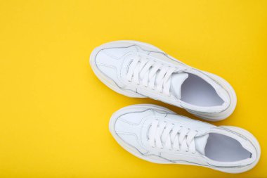 Sarı arka planda beyaz ayakkabılar.