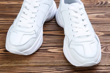 Kahverengi tahta masada bir çift beyaz ayakkabı.