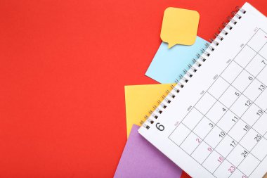 Kırmızı arkaplanda yapışkan notları olan takvim sayfası