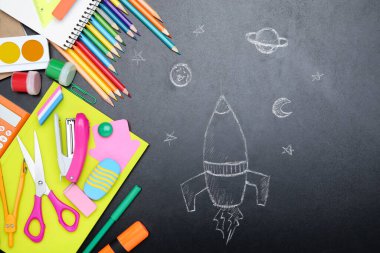 Tahta üzerine roket çizilmiş farklı okul malzemeleri.