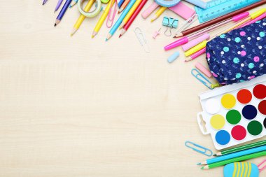 Kahverengi ahşap masada farklı okul malzemeleri var.