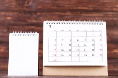 Kahverengi ahşap zemin üzerinde boş not defteri olan kağıt takvim sayfası
