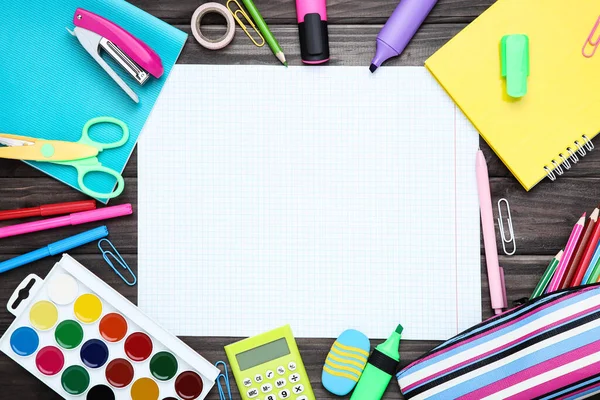 Tahta zemin üzerinde boş kağıt olan farklı okul malzemeleri.