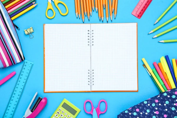 Mavi arka planda farklı okul malzemeleri olan boş bir kağıt.