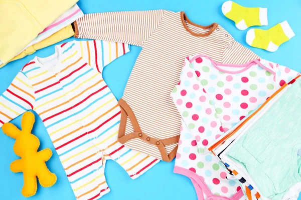 Mavi arka planda yumuşak tavşan oyuncağı olan bebek kıyafetleri.