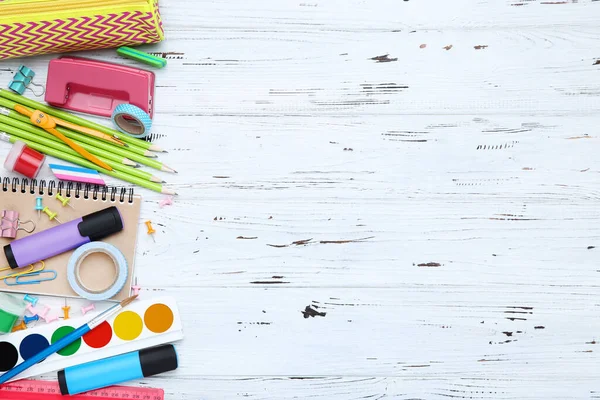 Beyaz ahşap arka planda farklı okul malzemeleri.