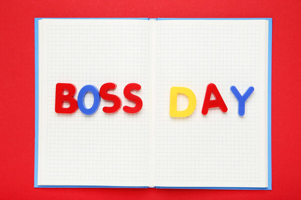 Colorful inscription Boss Day with notepad on red background