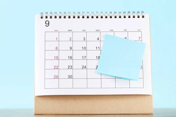 Calendar page with sticky note on blue background