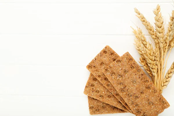 Beyaz ahşap masada buğday kulaklı çavdar ekmeği.