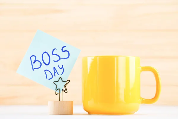 stock image Yellow cup and sticker with inscription Boss Day on wooden background