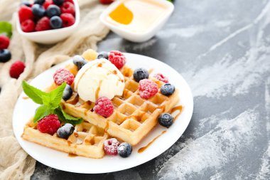 Taze böğürtlenli lezzetli waffle ve gri arka planda dondurma.