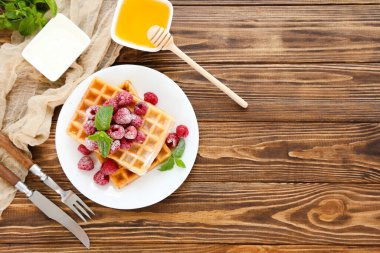 Taze ahududu ve kahverengi ahşap arka planda nane yapraklı lezzetli waffle 'lar.
