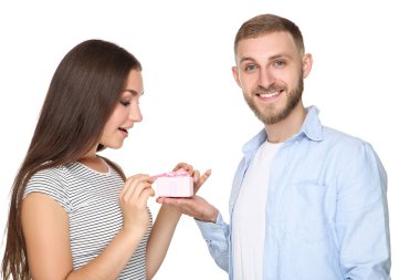 Genç adam beyaz arka planda kız arkadaşına hediye paketi veriyor.