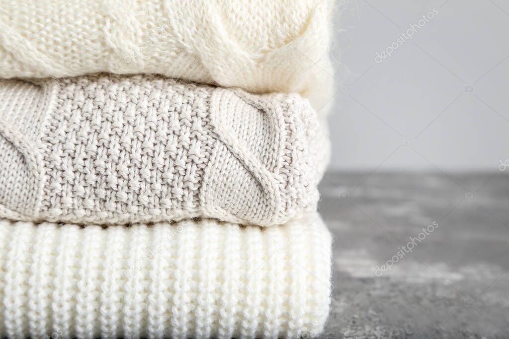 Folded sweaters on grey background