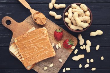 Fıstık ezmeli ekmek, ahşap masada meyve ve fındık.