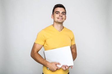 Gri arka planda bilgisayarlı genç adam