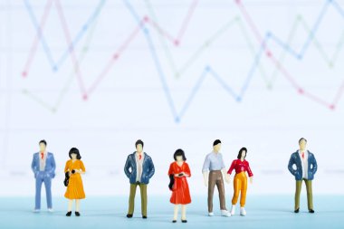 Grafik ve çizelgeleri olan minyatür insanlar ve finansal kağıtlar