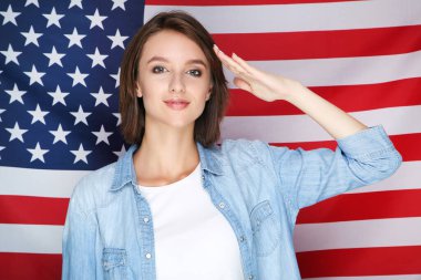 Güzel genç bir kadın Amerikan bayrağını selamlıyor.