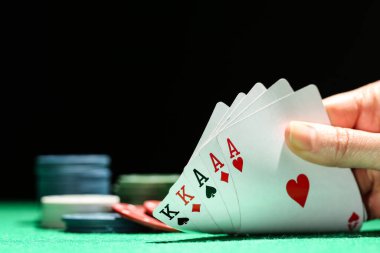 Poker fişleri ve kadın el kartları yeşil masada.