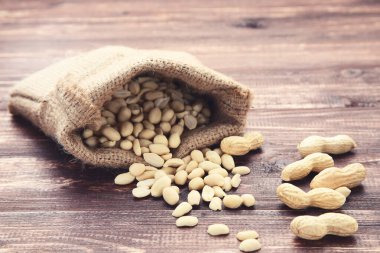 Kahverengi ahşap masadaki çuval bezinin içindeki fıstıklar