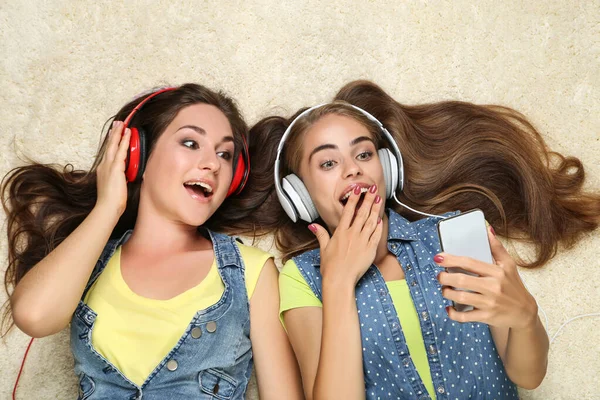 Fiatal Boldog Barátnők Fülhallgató Okostelefon Feküdt Szőnyegen — Stock Fotó
