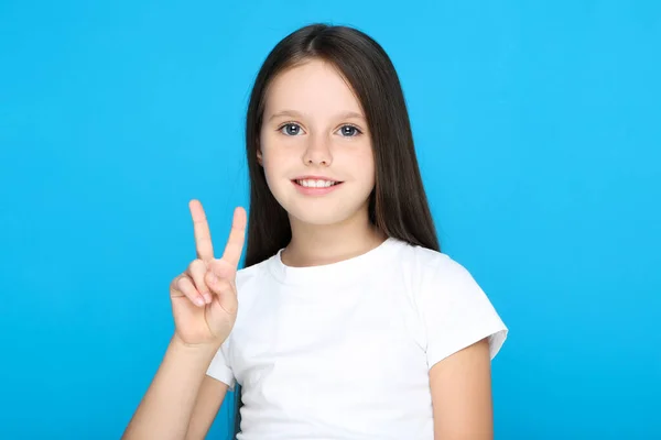 Young girl showing gesture by hands on blue background