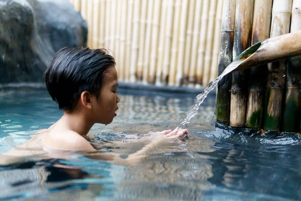Young asian boy talk and relax in hot water onzen