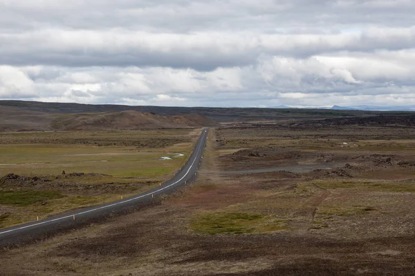 Strada vuota nel paesaggio rurale islandese Giornata estiva nuvolosa Campi infiniti di lava vulcanica e — Foto Stock