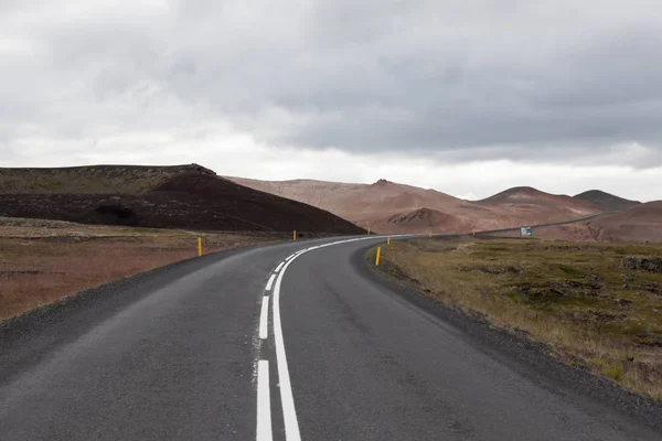 Islandia carretera con montañas marrones en el horizonte Camino vacío a su vez en el paisaje rural islandés — Foto de Stock