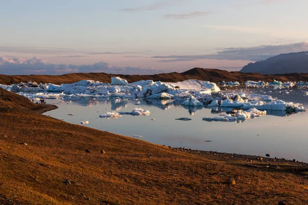 Atardecer rosa sobre icebergs derretidos cerca de la orilla de la laguna glaciar Jokulsarlon Nubes reflejadas en el —  Fotos de Stock