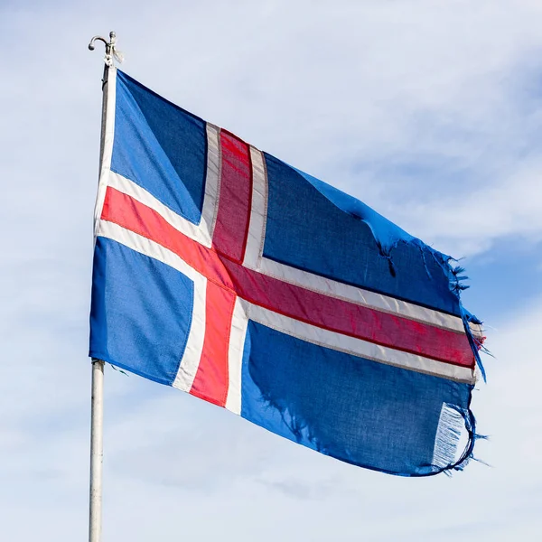 National flag of Iceland Old worn out textile flag torn on the edges waving in the wind Blue flag