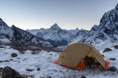 Ama Dablam 'ın karlı zirvesi karlı dağlarda mutfak malzemeleriyle dolu açık bir kamp çadırı.