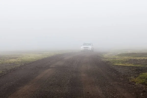 Coche en una niebla en un camino de tierra brumoso en Islandia Camino de niebla islandés — Foto de Stock