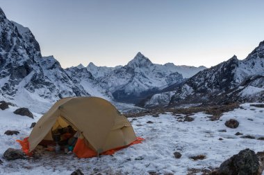 Ama Dablam 'ın karlı zirvesi karlı dağlarda mutfak malzemeleriyle dolu açık bir kamp çadırı.