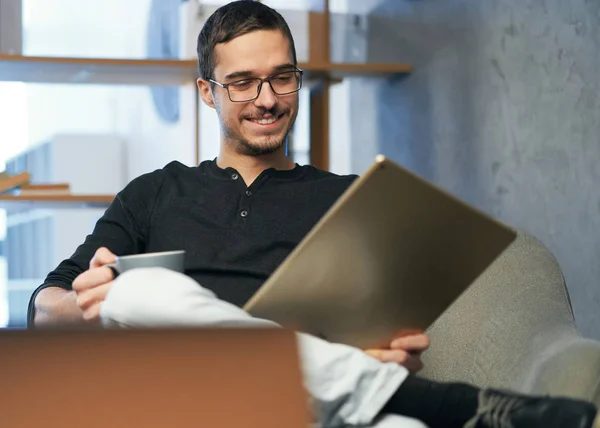 Joven trabajando con computadora, teléfono y tableta en la mesa mientras bebe café — Foto de Stock