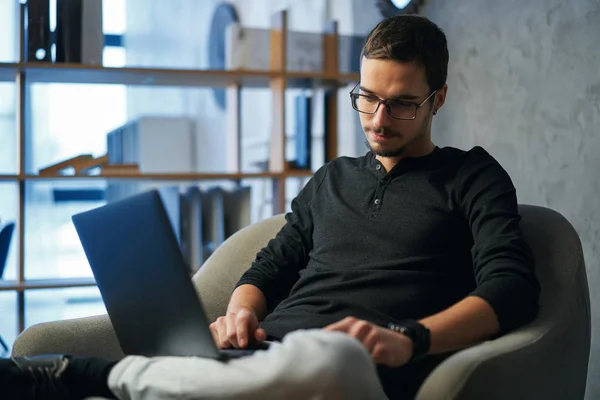 Giovane che lavora con computer, telefono e tablet a tavola mentre beve caffè — Foto Stock