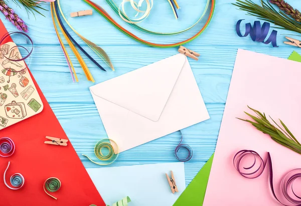 Envelope on blue wooden table with flowers, color pencils and cardboards — Stock Photo, Image