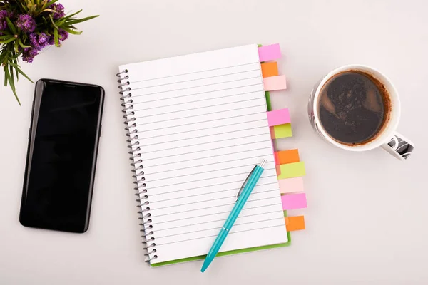 Planner sul tavolo da lavoro grigio con telefono e caffè. Libro bianco bianco sulla scrivania — Foto Stock