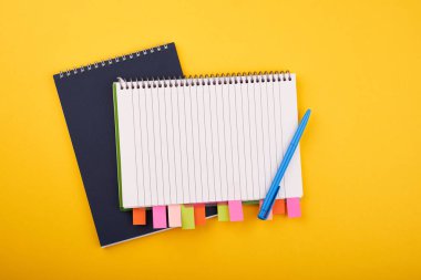 Sarı arka plan üzerinde renkli çıkartmalar ve mavi kalem içeren not defteri