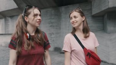 İki kız şehir merkezinde konuşuyor ve yürüyor.