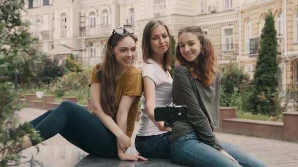 Tres chicas hermosas jóvenes haciendo selfie usando selfie-stick en el casco antiguo de Europa — Vídeos de Stock