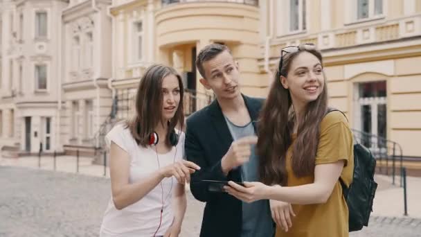 Grupa młodych przyjaciół turystów patrząc na mapę w smartfonie próbuje znaleźć właściwy sposób — Wideo stockowe