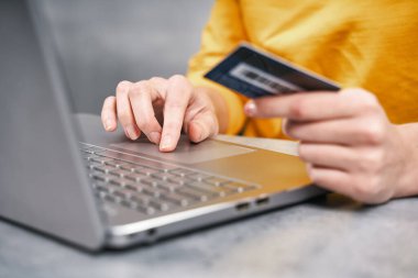 Kadının elindeki banka kartının yakın çekimi. Evden online alışveriş.