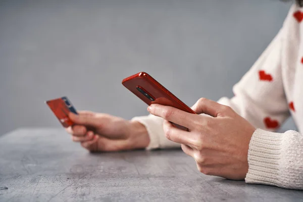 Woman hands with red phone and credit card. Shopping online