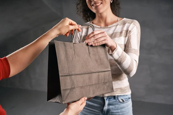 Жінка-кур'єр дає посилку клієнту в паперовій еко сумці Ліцензійні Стокові Зображення