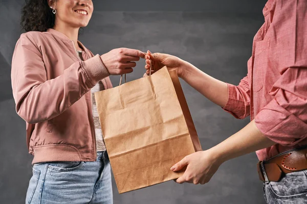Жінка-кур'єр дає посилку клієнту в паперовій еко сумці Ліцензійні Стокові Фото