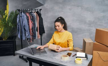 Kadın, dizüstü bilgisayarını kullanarak paket gönderiyor. Evden çalışmak